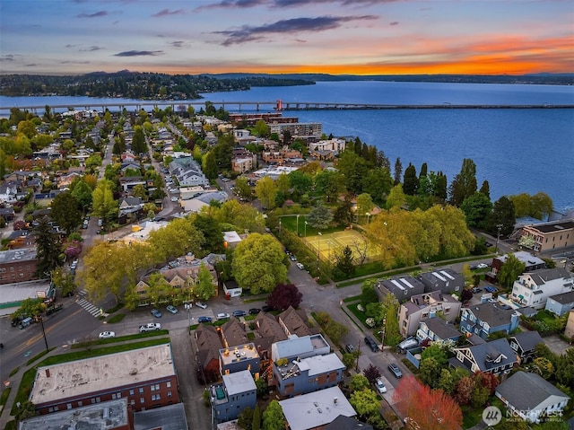 aerial view at dusk with a water view and a residential view