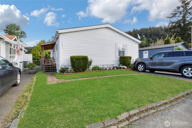 view of side of property featuring a lawn and fence