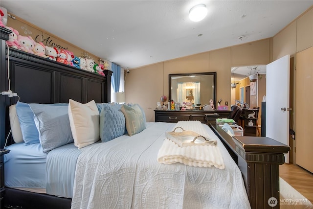 bedroom featuring light wood-style flooring and lofted ceiling