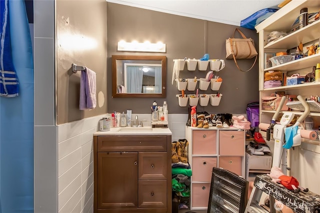 bathroom with vanity, wainscoting, and tile walls