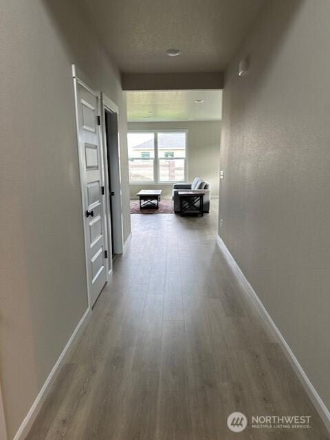 hall with baseboards and wood finished floors