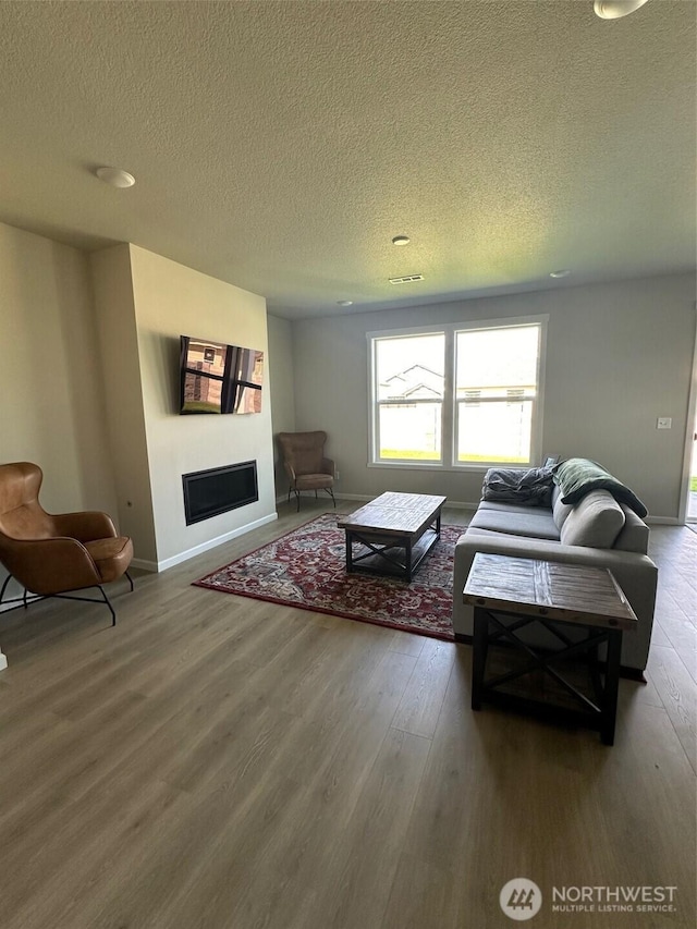 living area featuring baseboards, a textured ceiling, and wood finished floors