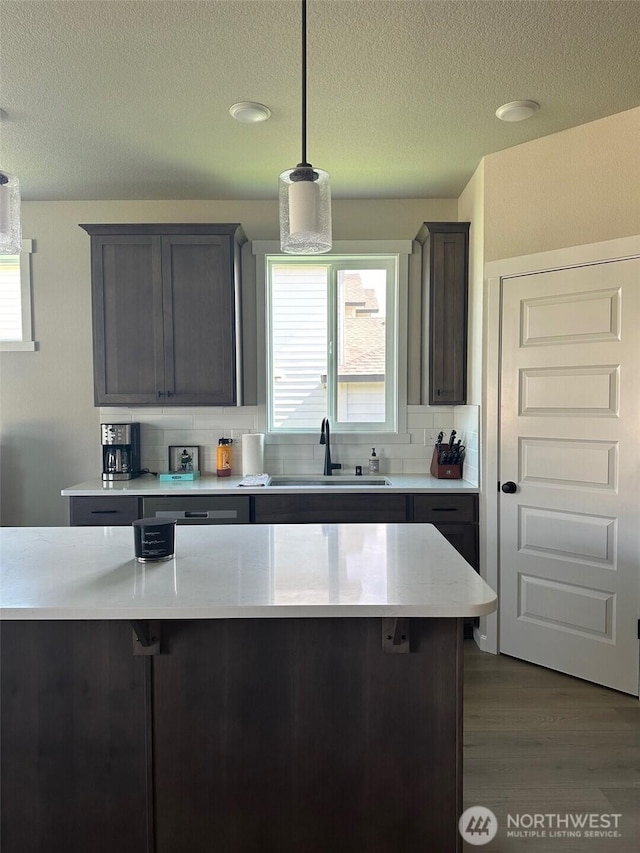kitchen with a sink, light countertops, decorative backsplash, and a healthy amount of sunlight