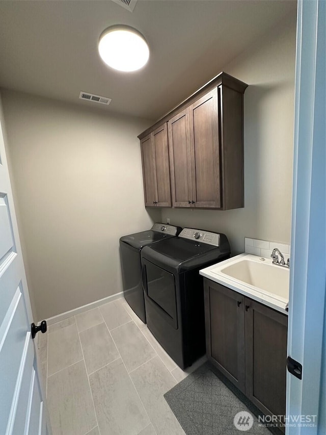 laundry area featuring visible vents, baseboards, separate washer and dryer, a sink, and cabinet space