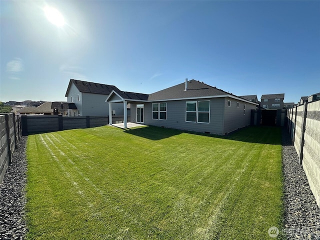 rear view of house with a fenced backyard, a patio, and a lawn
