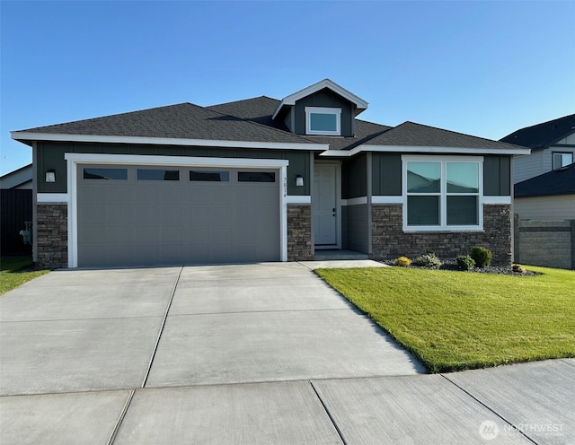 prairie-style home with an attached garage, a front yard, driveway, and stone siding