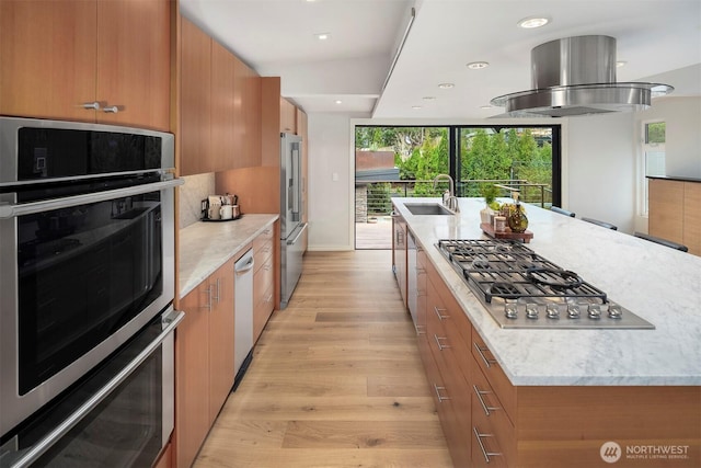 kitchen featuring brown cabinetry, island range hood, modern cabinets, a sink, and stainless steel appliances
