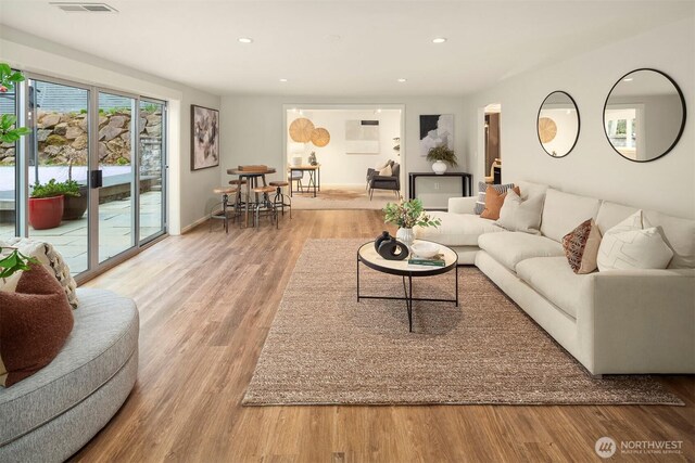 living room with recessed lighting, wood finished floors, and visible vents