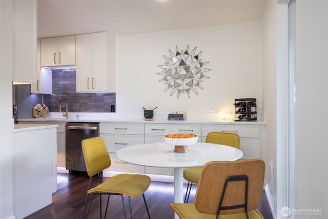 kitchen featuring a sink, backsplash, white cabinetry, dark wood-type flooring, and stainless steel dishwasher