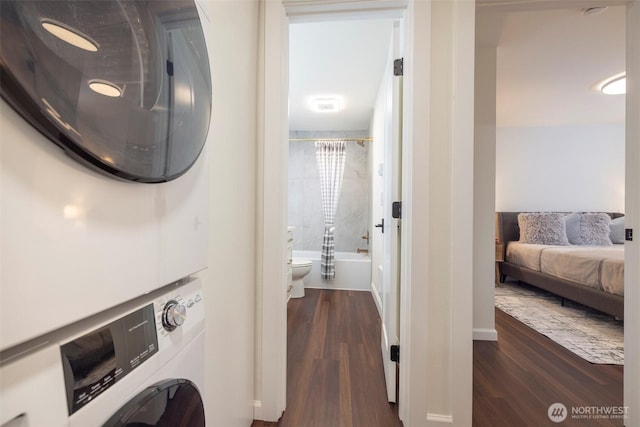laundry room with laundry area, dark wood-style flooring, and stacked washer / drying machine