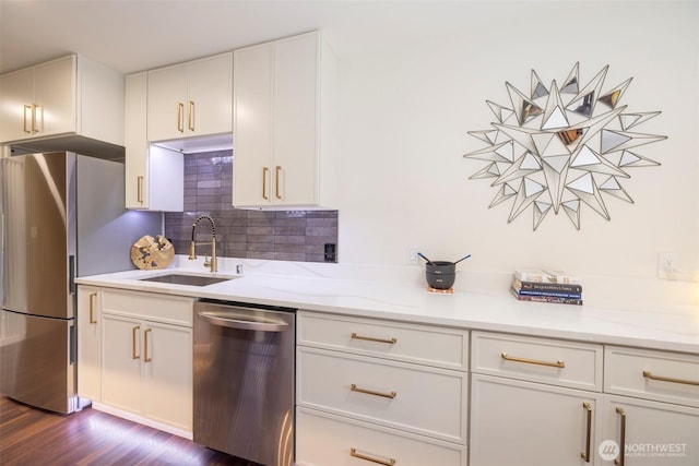 kitchen featuring decorative backsplash, dark wood-type flooring, white cabinetry, a sink, and appliances with stainless steel finishes