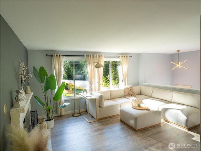 living area with baseboards, an inviting chandelier, and wood finished floors