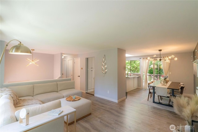 living area featuring baseboards, light wood-style flooring, and a chandelier