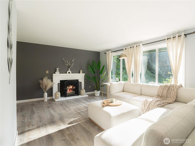 living area featuring baseboards, a fireplace, and wood finished floors