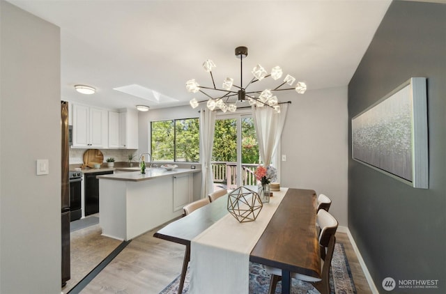 dining space featuring an inviting chandelier, light wood-style flooring, and a skylight