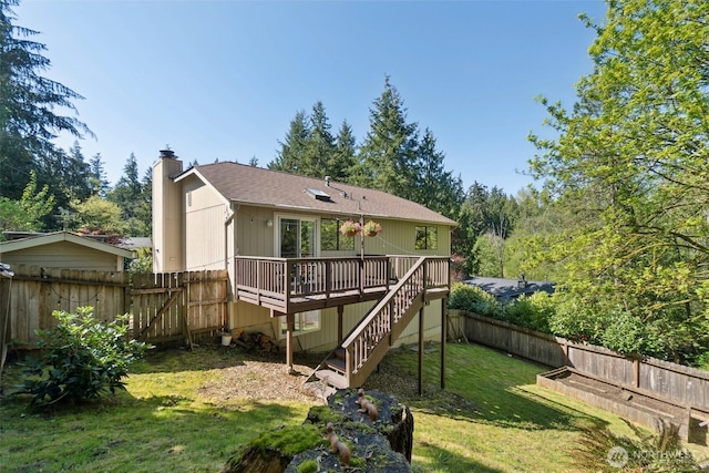 rear view of property with a chimney, a lawn, a deck, a fenced backyard, and stairs