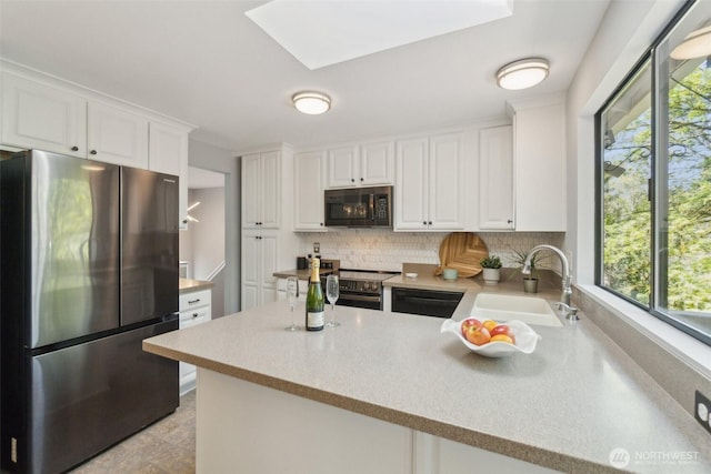 kitchen featuring white cabinets, appliances with stainless steel finishes, decorative backsplash, and a sink