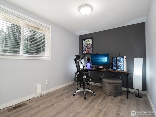 home office with baseboards, visible vents, and wood finished floors