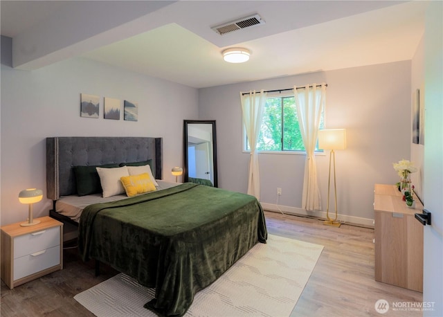 bedroom featuring baseboards, visible vents, and wood finished floors