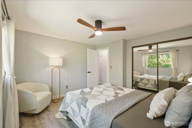 bedroom featuring light wood-type flooring, baseboards, ceiling fan, and a closet
