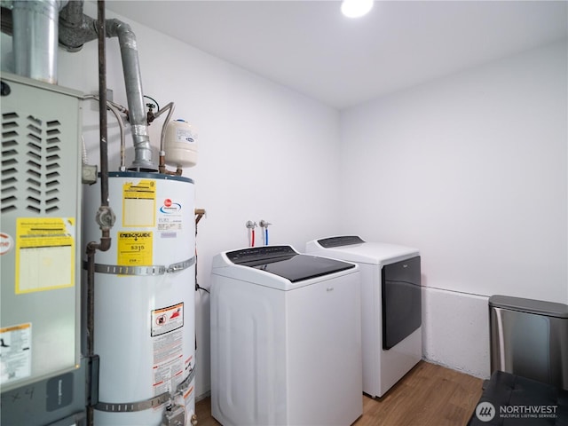 clothes washing area featuring washer and dryer, laundry area, light wood-style floors, water heater, and heating unit