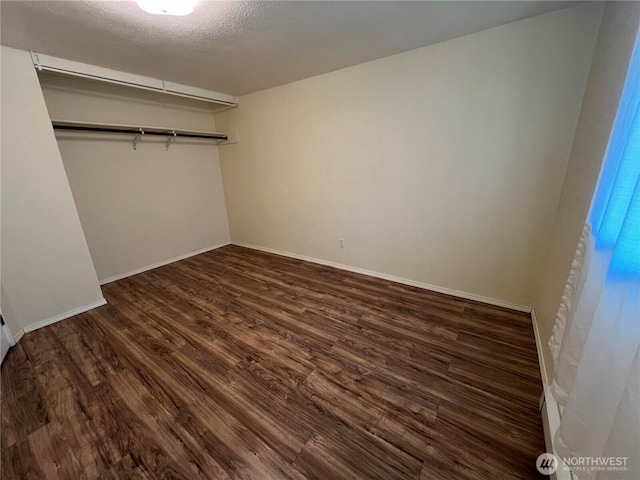 unfurnished bedroom featuring dark wood-style flooring, baseboards, and a closet