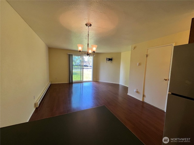 empty room featuring an inviting chandelier, wood finished floors, baseboards, a textured ceiling, and a baseboard heating unit