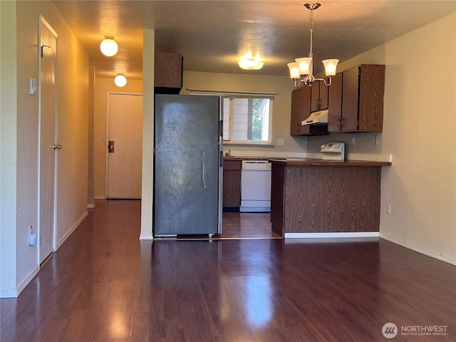 kitchen with freestanding refrigerator, white dishwasher, dark wood-style floors, under cabinet range hood, and a chandelier