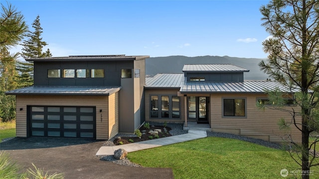 view of front facade featuring driveway, metal roof, a front yard, and a standing seam roof