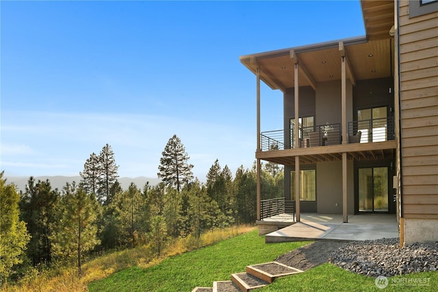 view of yard with a patio, a mountain view, and a balcony
