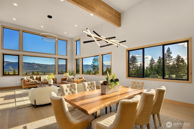 dining room featuring baseboards, recessed lighting, a high ceiling, and light wood-style flooring