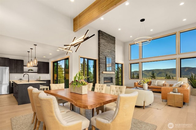 dining area featuring a towering ceiling, a notable chandelier, and light wood-style floors