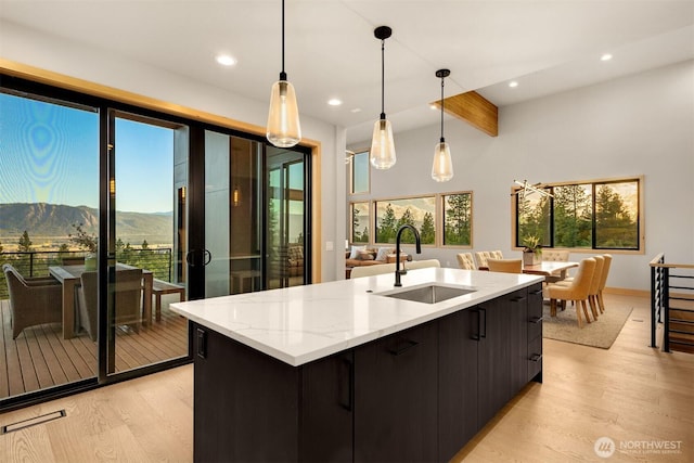 kitchen with a sink, a mountain view, light wood finished floors, and beam ceiling