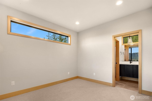 unfurnished bedroom featuring recessed lighting, light carpet, and multiple windows