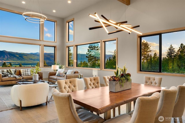 dining room with high vaulted ceiling, light wood finished floors, a mountain view, a chandelier, and recessed lighting