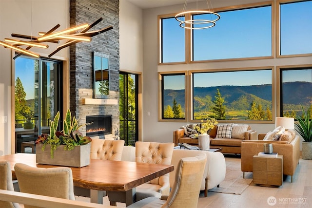 interior space with a towering ceiling, a wealth of natural light, a stone fireplace, and a notable chandelier
