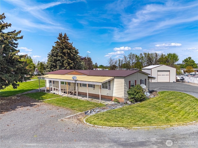 view of front of home with metal roof, driveway, a front yard, and a detached garage