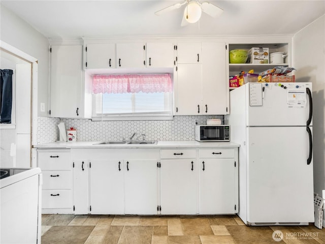 kitchen featuring black microwave, a sink, light countertops, stove, and freestanding refrigerator