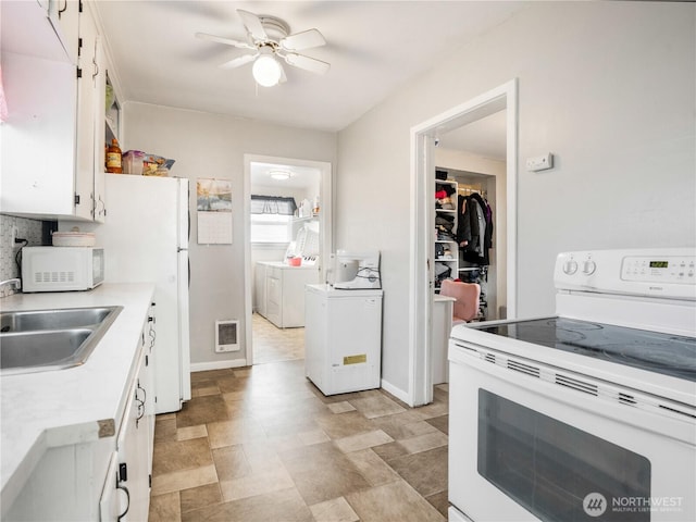 kitchen featuring a ceiling fan, a sink, light countertops, white cabinets, and white appliances
