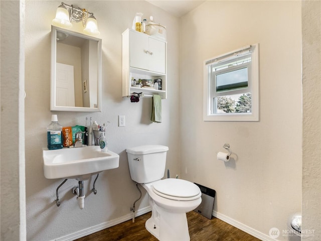 bathroom featuring baseboards, wood finished floors, and toilet