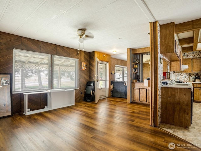 kitchen with light countertops, ceiling fan, wooden walls, and wood finished floors