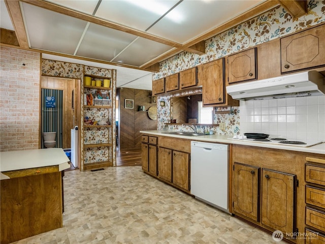 kitchen featuring light countertops, brown cabinets, under cabinet range hood, and white appliances