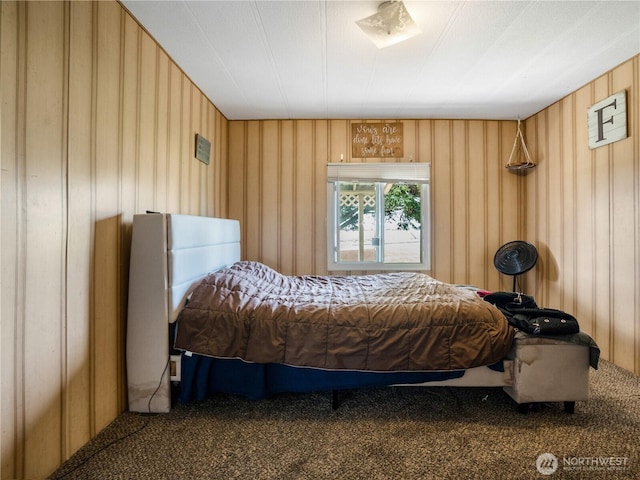 carpeted bedroom featuring wood walls