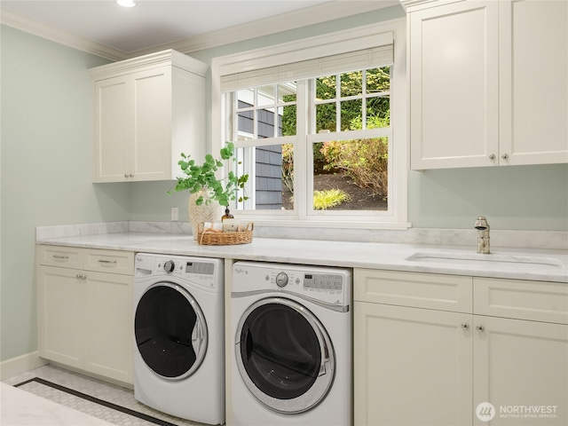 washroom featuring washing machine and clothes dryer, cabinet space, a sink, baseboards, and ornamental molding