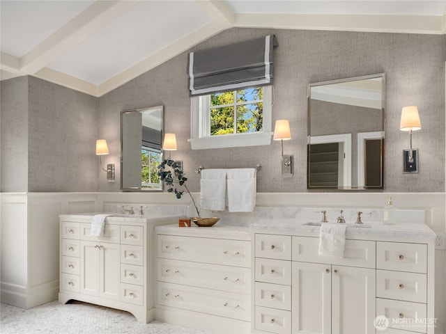 full bathroom with vanity, wainscoting, wallpapered walls, and lofted ceiling