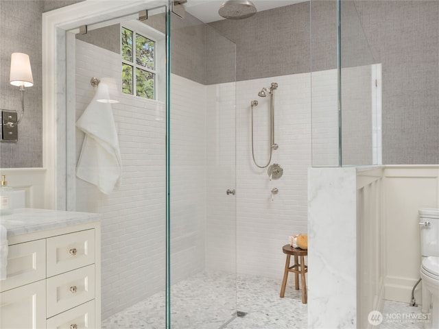 full bathroom featuring vanity, wainscoting, toilet, and tiled shower