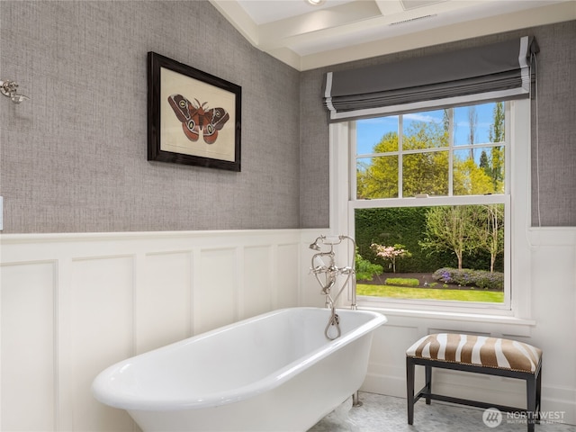 bathroom featuring wainscoting, a freestanding bath, and a decorative wall
