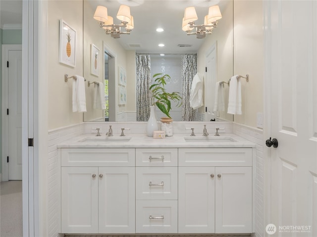 bathroom featuring double vanity, a chandelier, and a sink