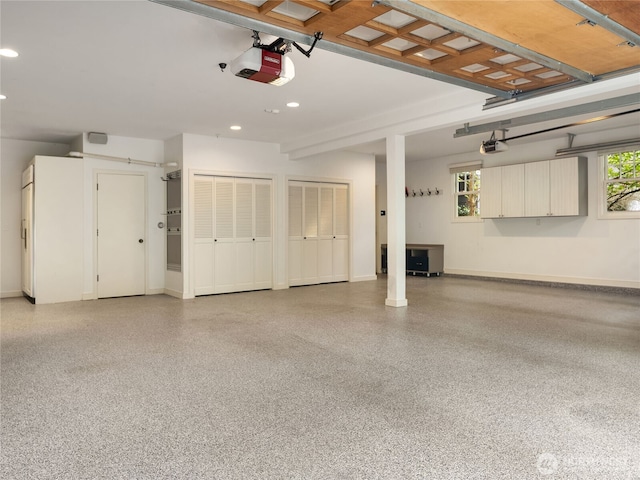 garage featuring baseboards, a garage door opener, and recessed lighting