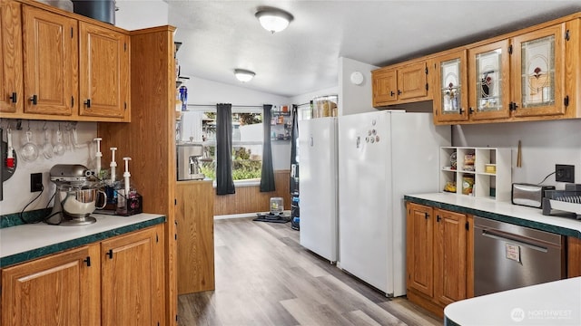 kitchen featuring stainless steel dishwasher, freestanding refrigerator, vaulted ceiling, light wood-type flooring, and brown cabinets
